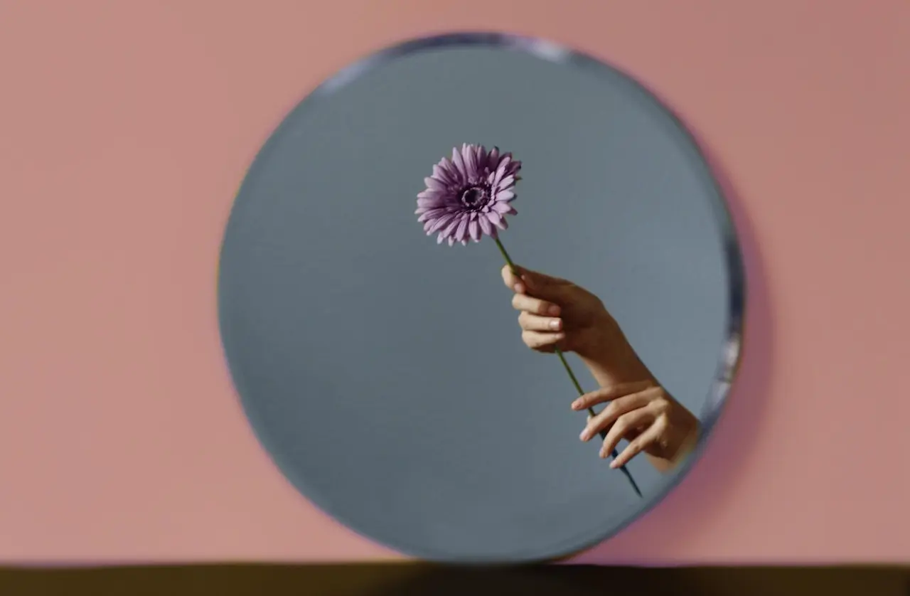 فردی گلی را با دستانش در آیینه گرفته است